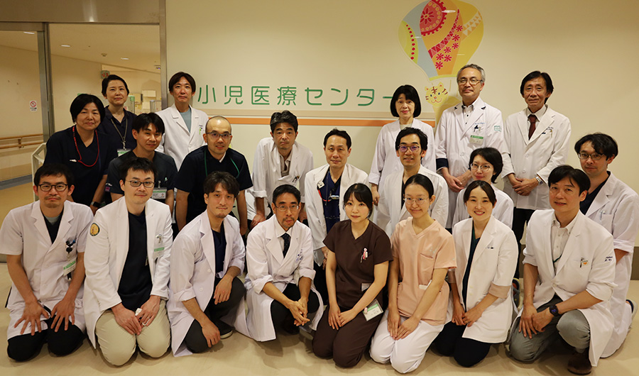 小児医療センターの前に立つ小児がん診療スタッフの集合写真